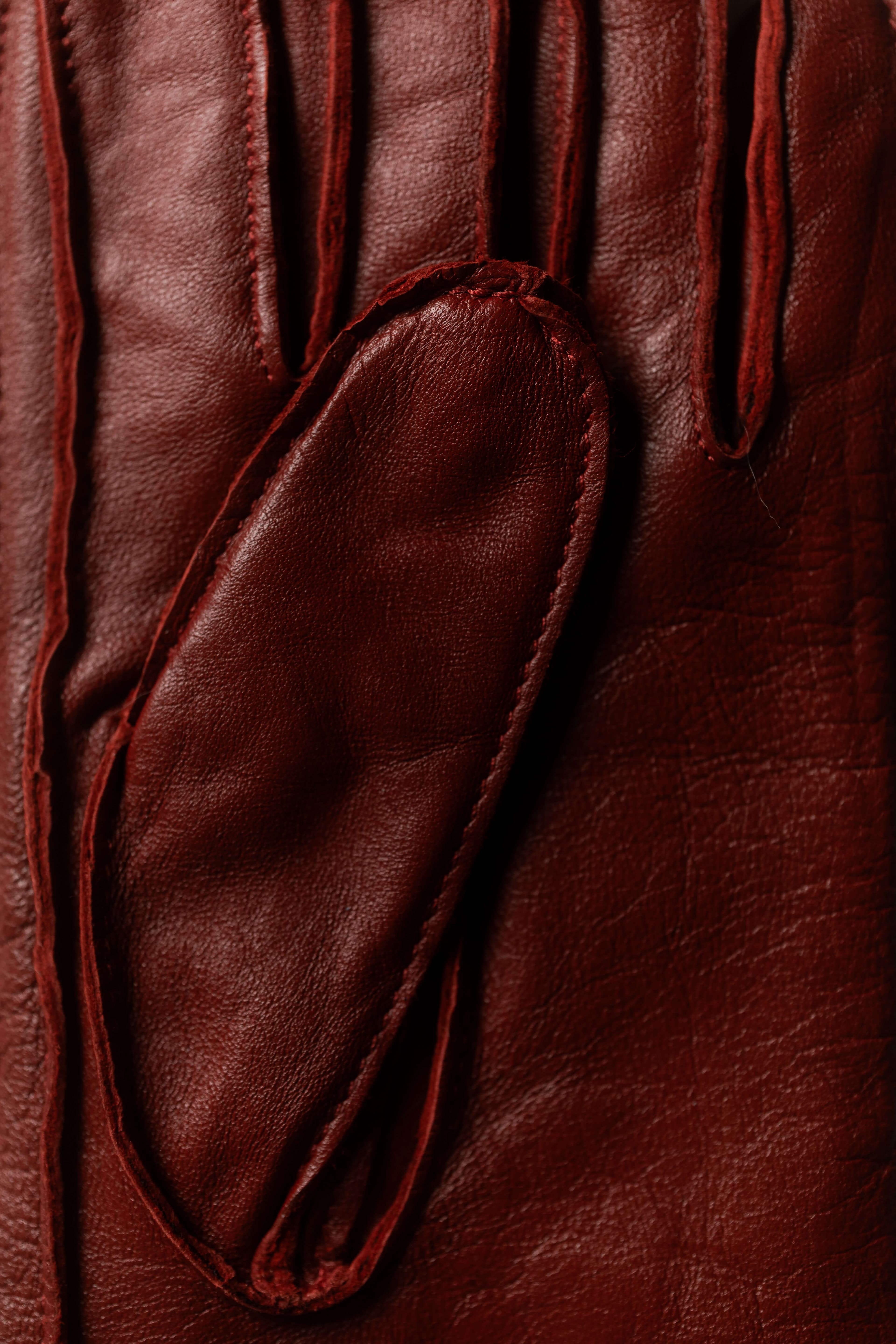 A close-up of a rich burgundy leather glove, showing its soft texture and stitching detail