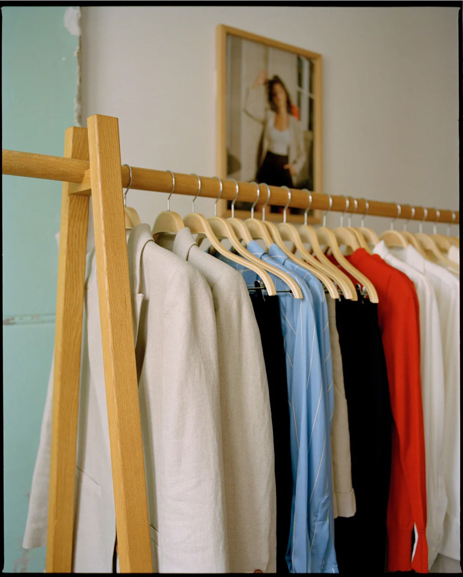 Wooden rail of shirts and jackets in a sunlit studio